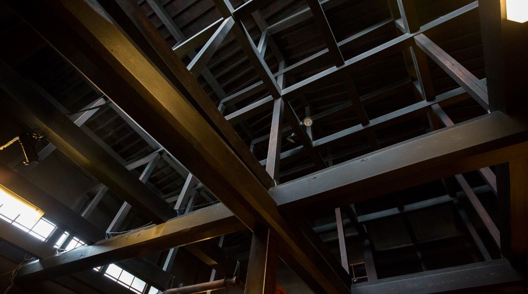 入館してすぐに天井を見上げると、7間半（約13m）の1本の赤松で貫き通されたスケールの大きな梁に圧倒。 3Fの高さまである吹き抜けで開放感溢れる空間をお楽しみ下さい。